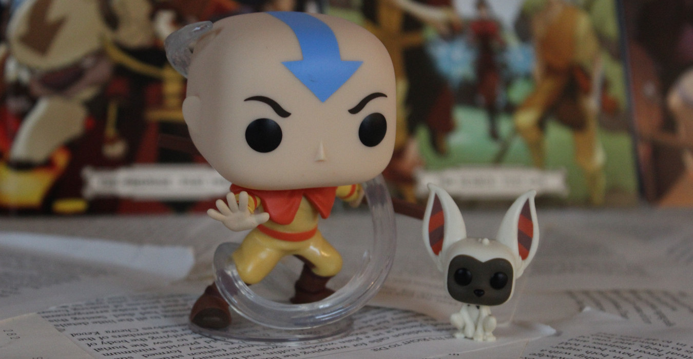 A funko pop figurine of Aang from Avatar: The Last Airbender. Next to him is a small funko of Momo, a lemur-like creature.