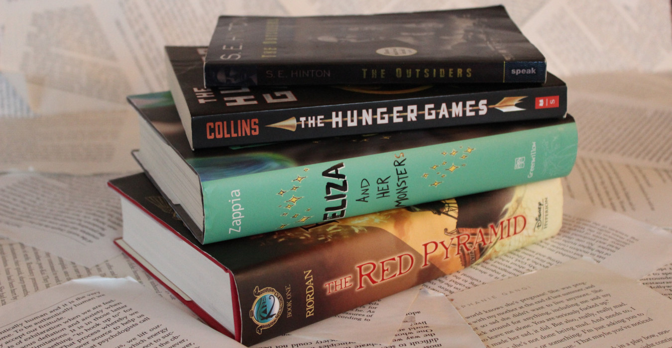 A stack of four books slightly fanned out. From top to bottom, they are The Outsders, The Hunger Games, Eliza and Her Monsters, and The Red Pyramid.