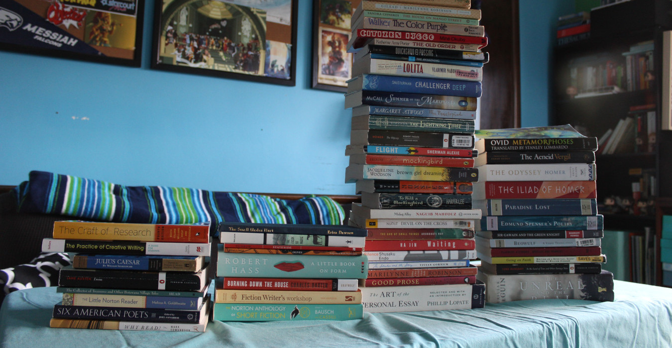 Four stacks of books on a table. The third stack from the left is the tallest.