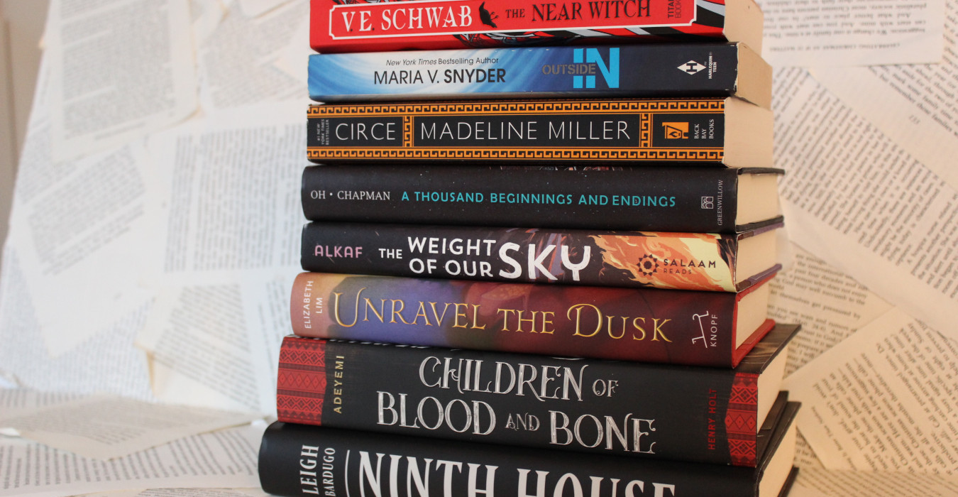 A stack of books. From top to bottom, they are: The Near Witch, Outside In, Circe, A Thousand Beginnings and Endings, The Weight of our Sky, Unravel the Dusk, Children of Blood and Bone, and Ninth House.