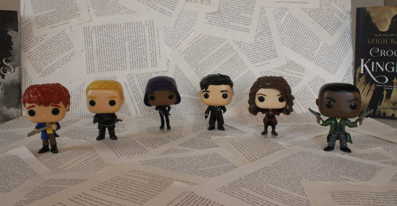 6 Funko Pop figurines based on the characters from Six of Crow. From left to right, they are Wylan, Matthias, Inej, Kaz, Nina, and Jesper.