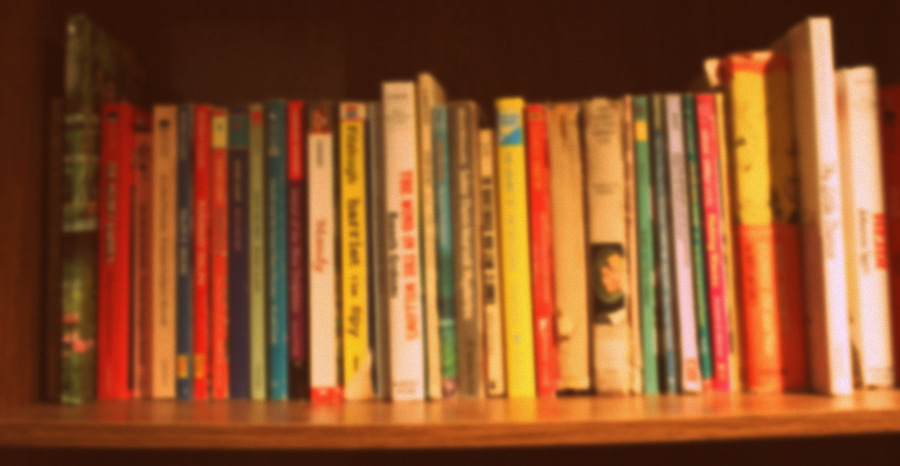 A bookshelf filled with many older-looking books. Some of them may even be considered vintage.