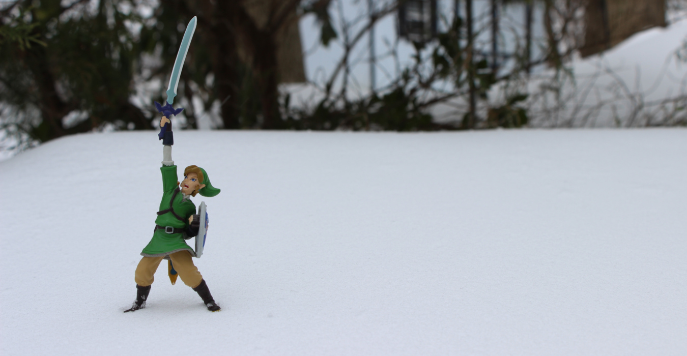 A small figurine of Link from The Legend of Zelda: Skyward Sword sits on a wintry background in the snow.