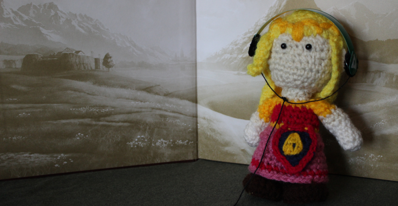 A handmade, crocheted plush doll of Zelda from The Legend of Zelda stands against an illustrated background. The dolls is wearing over-ear headphones.