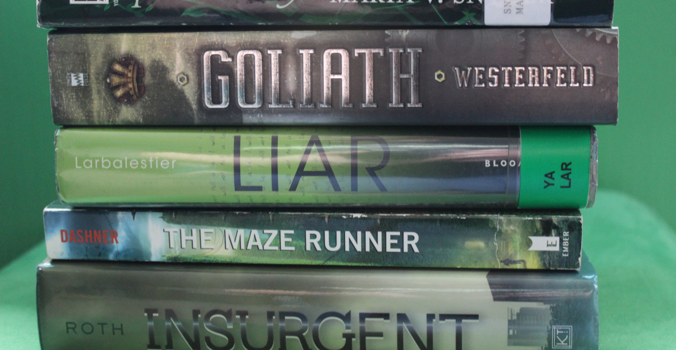 A stack of green books on a green background. From top to bottom, they are: Goliath, Liar, The Maze Runner, and Insurgent.