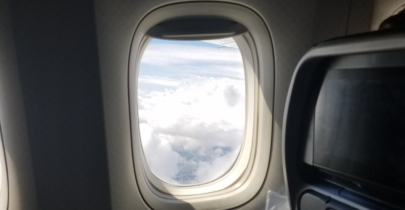 A photo looking out of an airplane window. Clouds can be seen outside