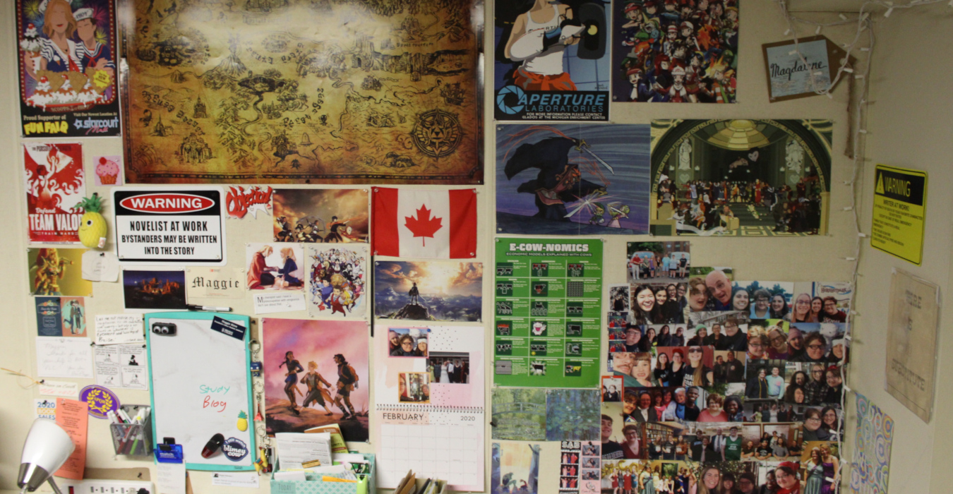 A photo depicting a wall decorated with photographs, posters, and other found objects. The wall is almost compltely full